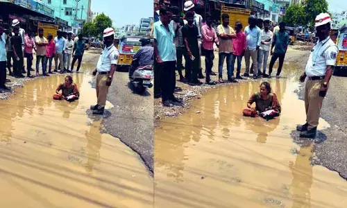 నడిరోడ్డుపై మహిళ వినూత్న పోరాటం.. రోడ్డుపై ఉన్న నీటి గుంతలో దిగి నిరసన.. ఎందుకంటే?